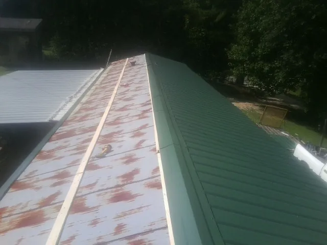 Old rusted panels beside newly installed green metal roofing — Wind Damage Roof Repair by Roofing Brothers in Dyer