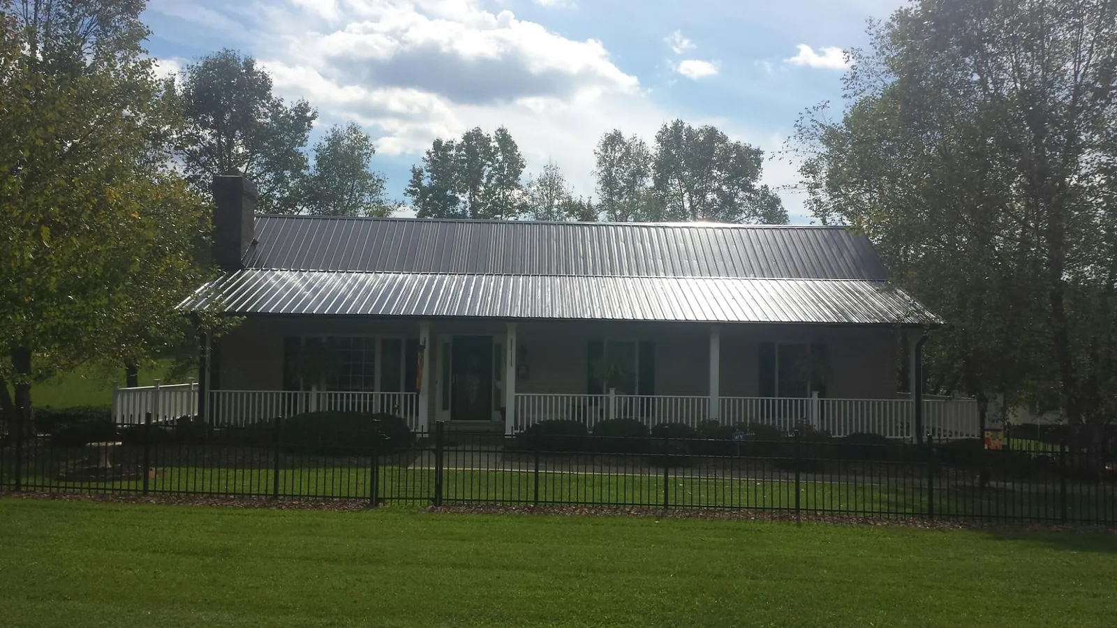 Gray metal roof on a brick ranch with a full width front porch — Gutter Guard Installation work by our crew in Dyer